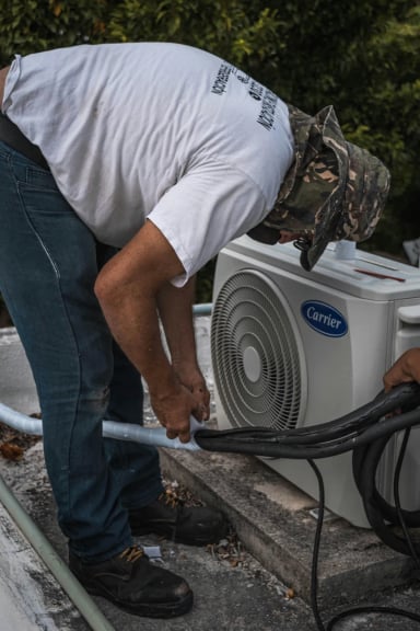 Technician working on a Carrier air conditioning unit on a rooftop